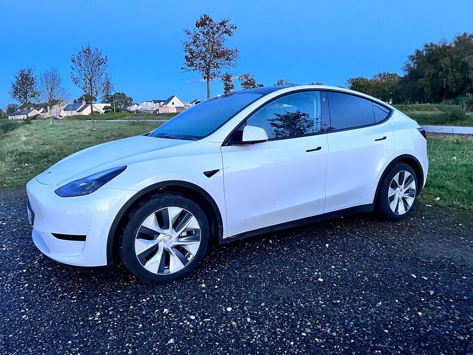 A white Tesla Model Y parked in a rural setting